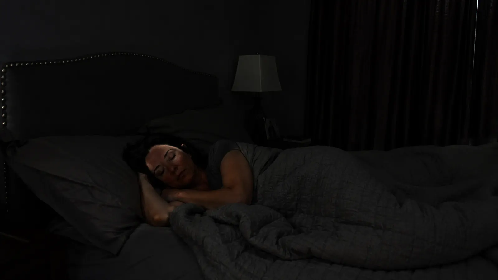Bedroom fully dark at 6am with curtains closed, person still asleep