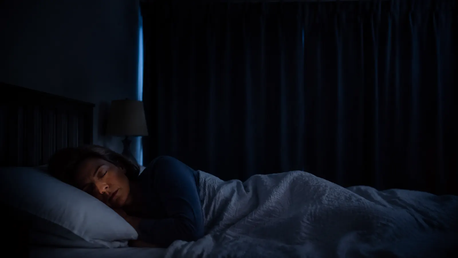 A fully darkened bedroom at night with blackout curtains closed and no visible light leaking through
